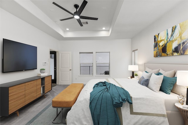 carpeted bedroom featuring a raised ceiling and ceiling fan