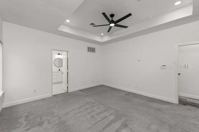 carpeted empty room featuring a tray ceiling and ceiling fan