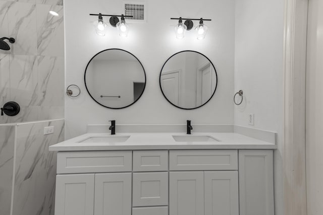 bathroom with a tile shower and vanity