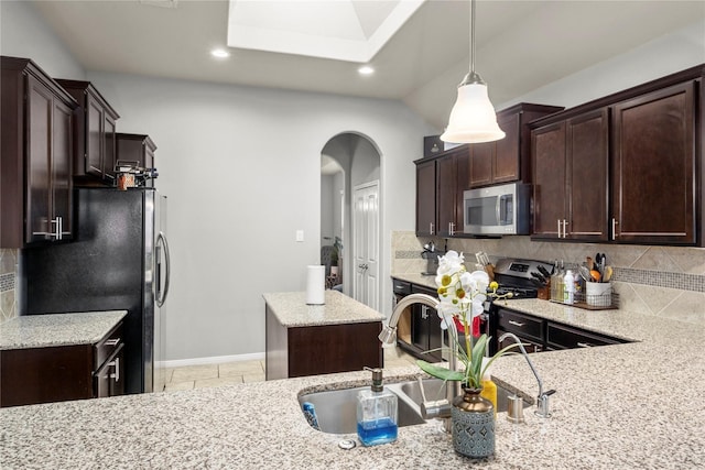 kitchen with light stone countertops, sink, tasteful backsplash, pendant lighting, and appliances with stainless steel finishes