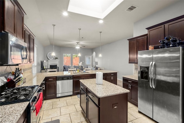 kitchen with sink, ceiling fan, appliances with stainless steel finishes, a kitchen island, and kitchen peninsula