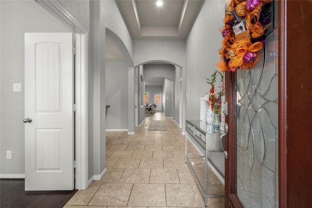 corridor featuring a raised ceiling and light tile patterned floors