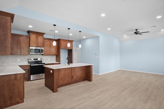 kitchen featuring a center island with sink, hanging light fixtures, ceiling fan, tasteful backsplash, and stainless steel appliances