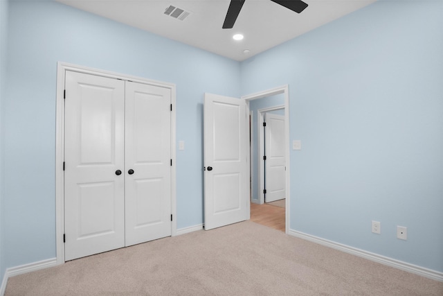 unfurnished bedroom featuring light carpet, a closet, and ceiling fan