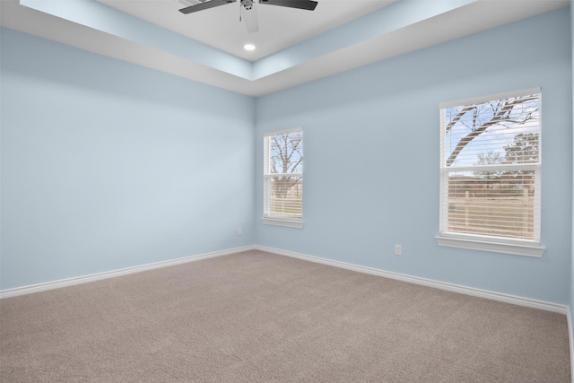 empty room featuring carpet floors, a raised ceiling, and ceiling fan