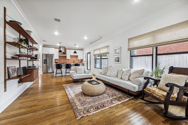 living room with dark wood-type flooring and ornamental molding