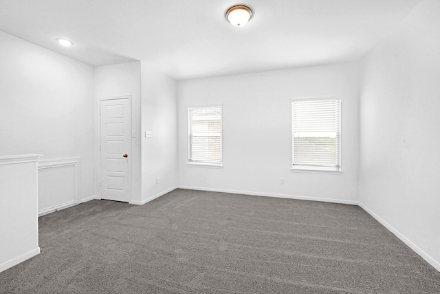 empty room featuring plenty of natural light and dark carpet