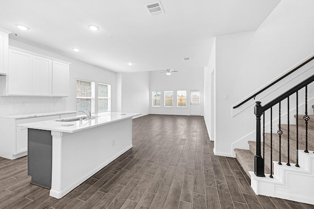 kitchen with a center island with sink, white cabinetry, ceiling fan, and sink