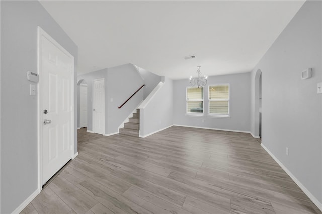 unfurnished living room featuring light hardwood / wood-style flooring and a notable chandelier