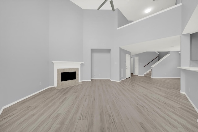 unfurnished living room featuring light hardwood / wood-style floors, a fireplace, and a high ceiling