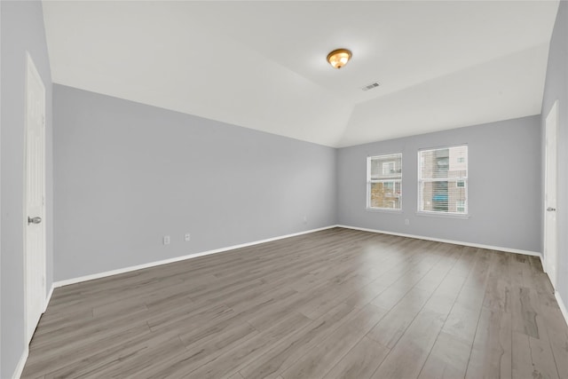 empty room with light hardwood / wood-style floors and lofted ceiling