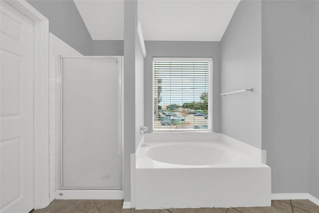 bathroom with tile patterned flooring, separate shower and tub, and vaulted ceiling