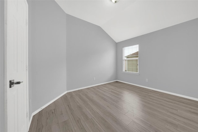 unfurnished room featuring lofted ceiling and light hardwood / wood-style flooring