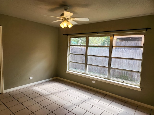 empty room featuring ceiling fan, light tile patterned floors, and a textured ceiling