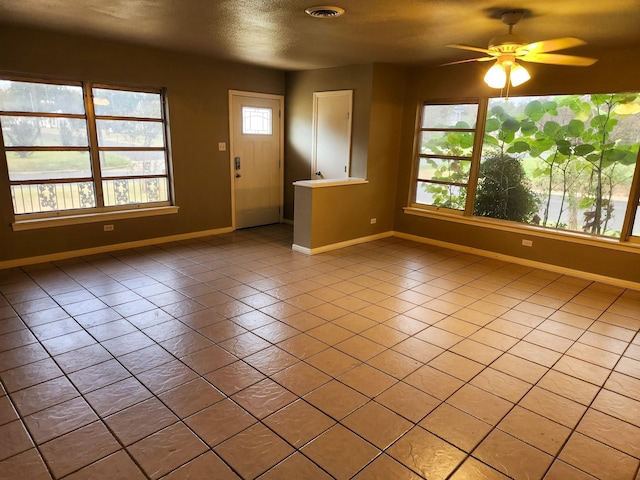 entrance foyer with ceiling fan, plenty of natural light, light tile patterned floors, and a textured ceiling