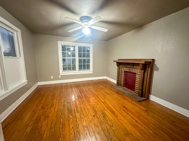 unfurnished living room featuring a fireplace, hardwood / wood-style floors, a textured ceiling, and ceiling fan