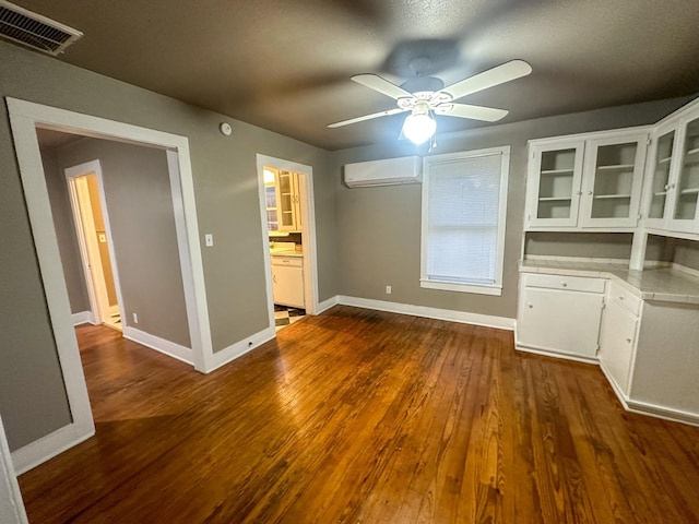 unfurnished dining area with a wall mounted air conditioner, ceiling fan, and dark wood-type flooring