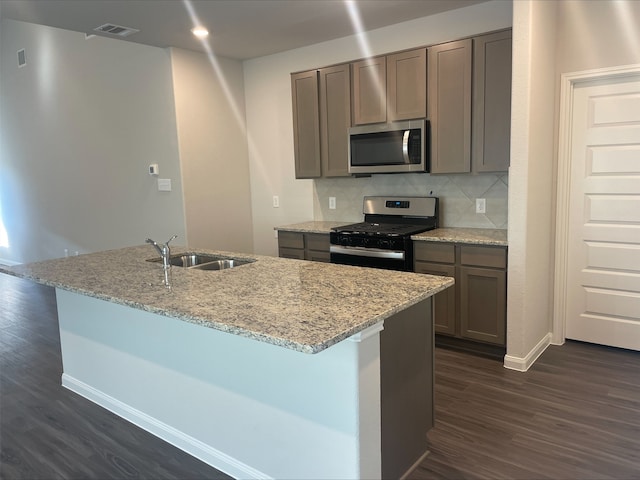 kitchen with light stone countertops, decorative backsplash, dark wood-type flooring, and stainless steel appliances