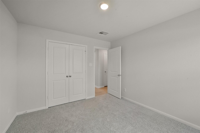 unfurnished bedroom with light carpet and a closet