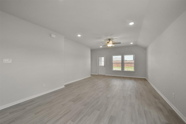 empty room with ceiling fan, lofted ceiling, and light wood-type flooring