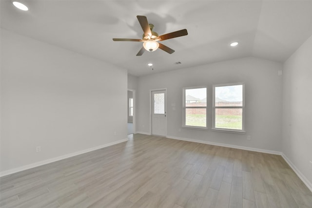 spare room with ceiling fan, vaulted ceiling, and light wood-type flooring