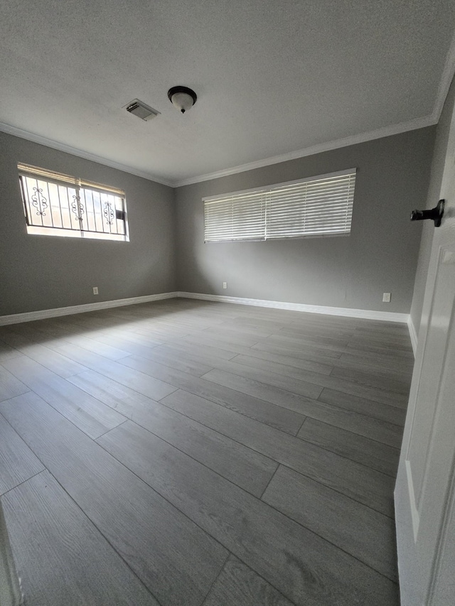 spare room featuring wood-type flooring, a textured ceiling, and ornamental molding