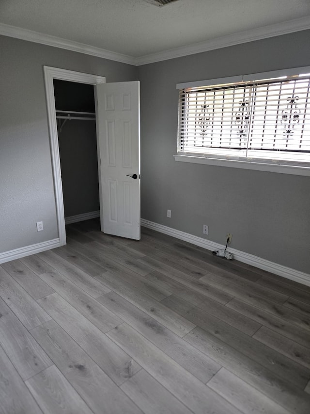 unfurnished bedroom with light hardwood / wood-style floors, a closet, and ornamental molding