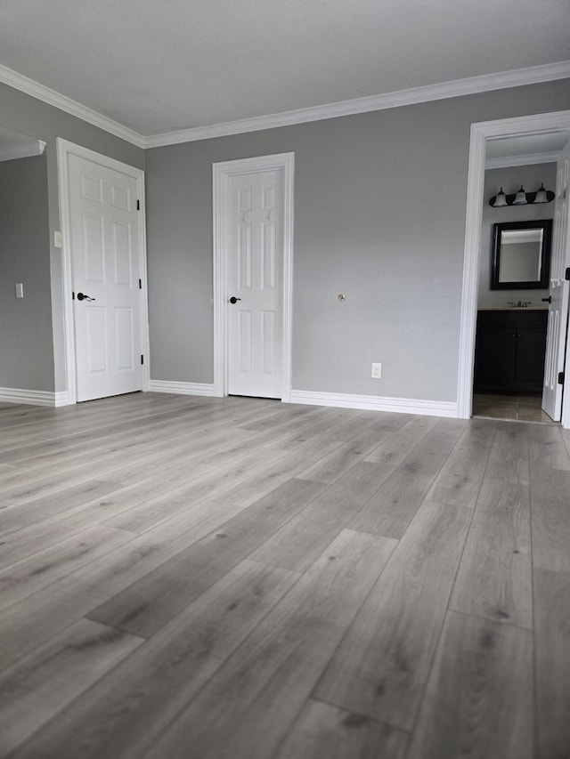 empty room featuring light wood-type flooring and crown molding