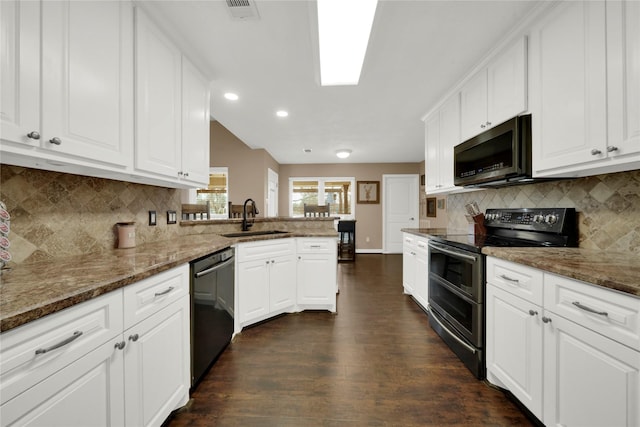 kitchen featuring dark stone countertops, kitchen peninsula, sink, white cabinetry, and appliances with stainless steel finishes