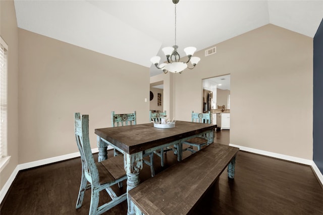 dining area featuring lofted ceiling, dark hardwood / wood-style flooring, and an inviting chandelier