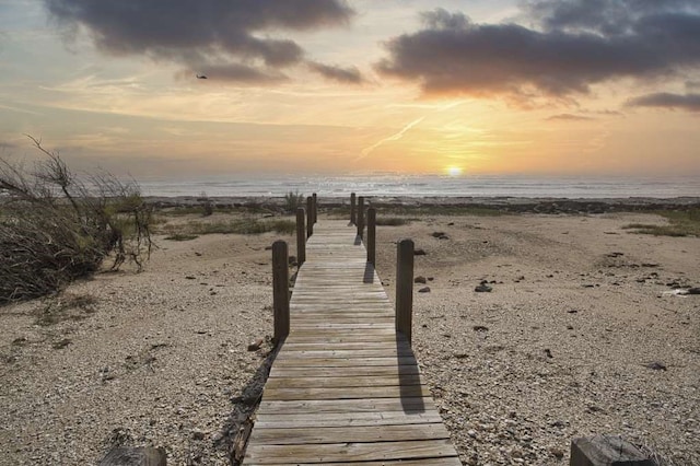 view of dock featuring a beach view and a water view