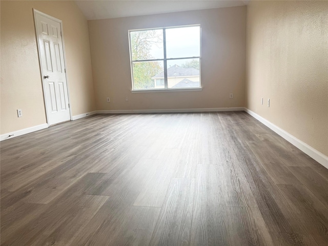 unfurnished room featuring dark hardwood / wood-style floors and vaulted ceiling