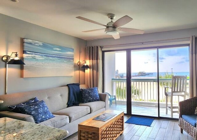 living room featuring a wealth of natural light, light hardwood / wood-style floors, ceiling fan, and a water view