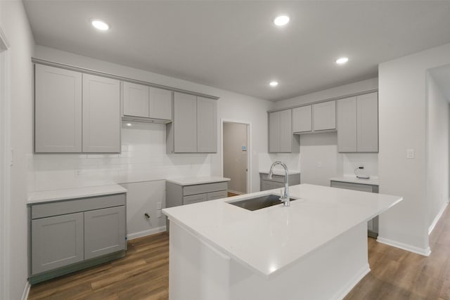 kitchen featuring gray cabinetry, sink, and an island with sink