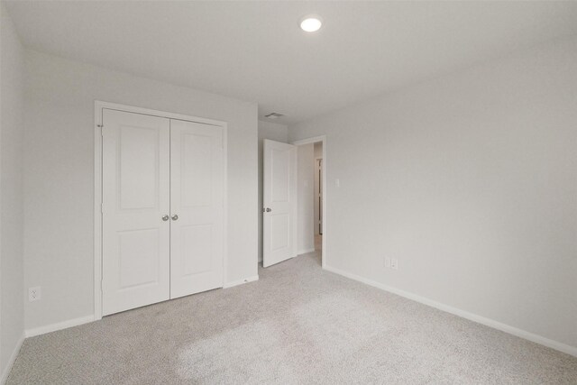 unfurnished bedroom with light carpet and a closet