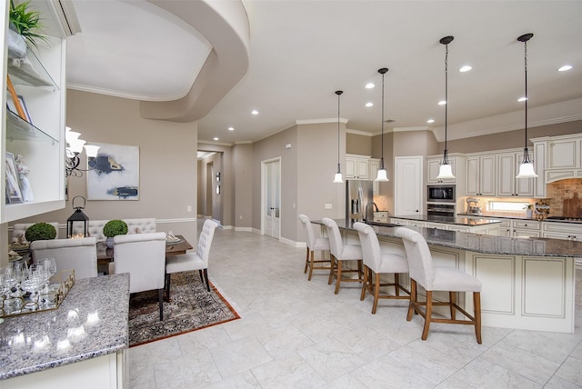 kitchen featuring a kitchen bar, hanging light fixtures, appliances with stainless steel finishes, and dark stone counters