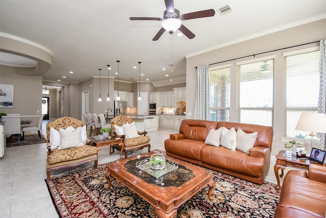 living room with ceiling fan, ornamental molding, and sink