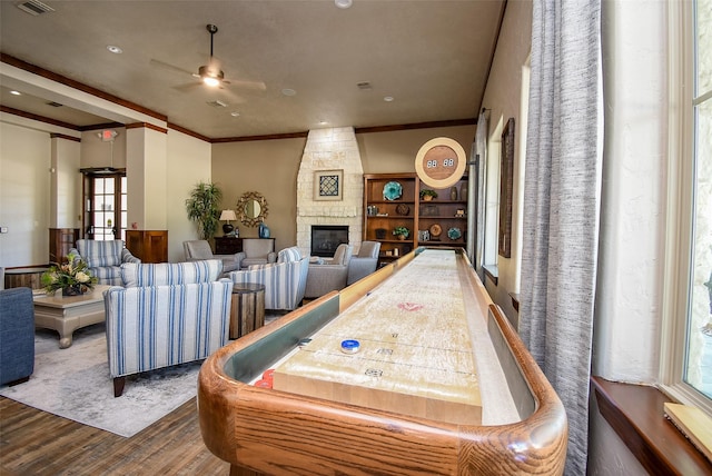 rec room featuring ceiling fan, a fireplace, dark wood-type flooring, and plenty of natural light