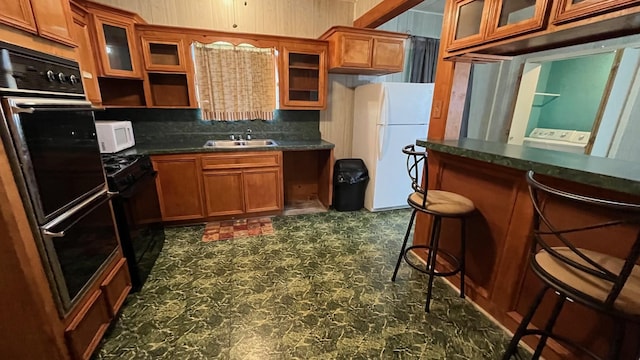 kitchen with black appliances, a breakfast bar, backsplash, and sink