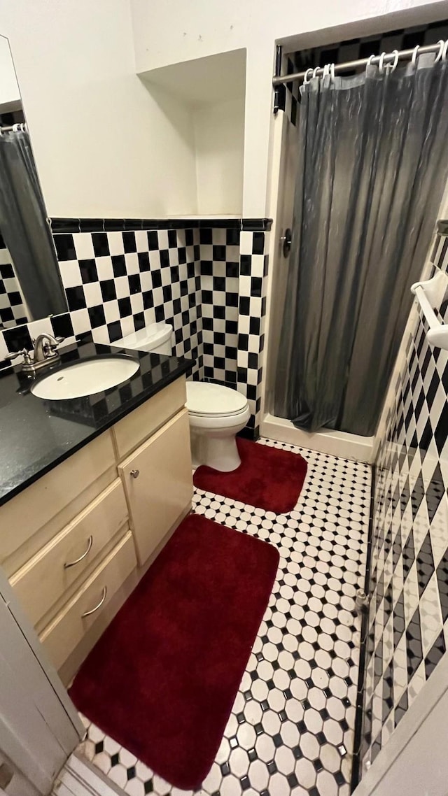 bathroom featuring a shower with curtain, vanity, toilet, and tile walls