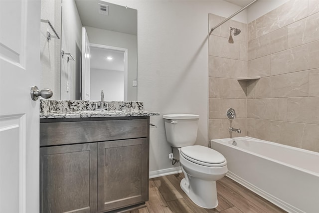 full bathroom featuring vanity, tiled shower / bath combo, and toilet