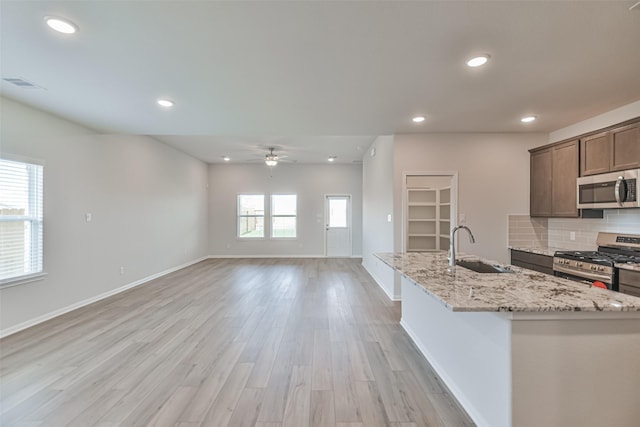 kitchen featuring plenty of natural light, sink, light stone countertops, and stainless steel appliances