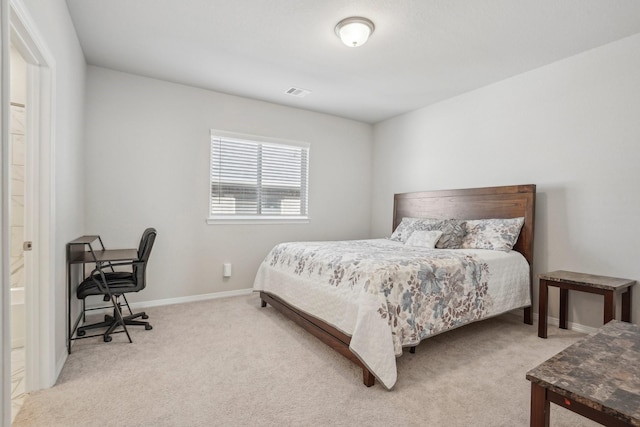 bedroom with ensuite bath and light colored carpet