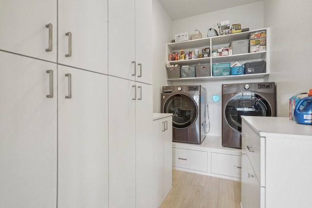 clothes washing area featuring cabinets, separate washer and dryer, and light wood-type flooring