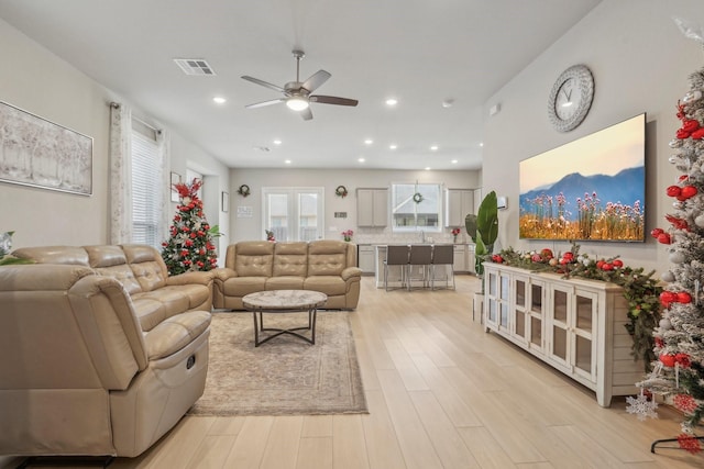 living room with a ceiling fan, recessed lighting, visible vents, and light wood finished floors