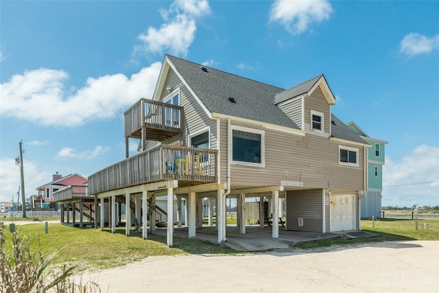 rear view of property with a lawn, a wooden deck, a carport, and a garage