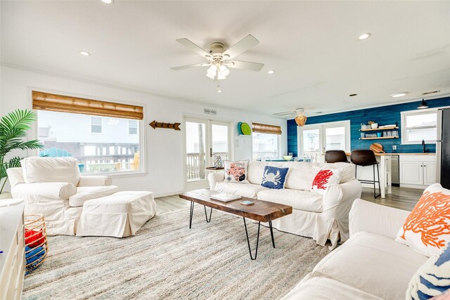 living room featuring ceiling fan, light hardwood / wood-style floors, ornamental molding, and sink