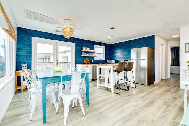 dining space with ceiling fan, sink, light wood-type flooring, and crown molding