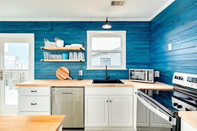 kitchen featuring white cabinetry, sink, wooden counters, appliances with stainless steel finishes, and ornamental molding