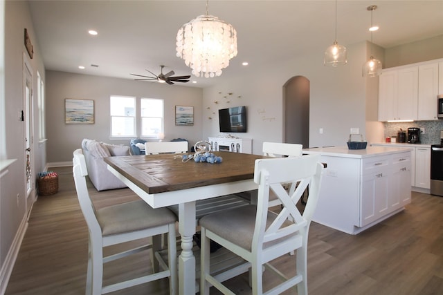 dining room featuring ceiling fan with notable chandelier and dark wood-type flooring